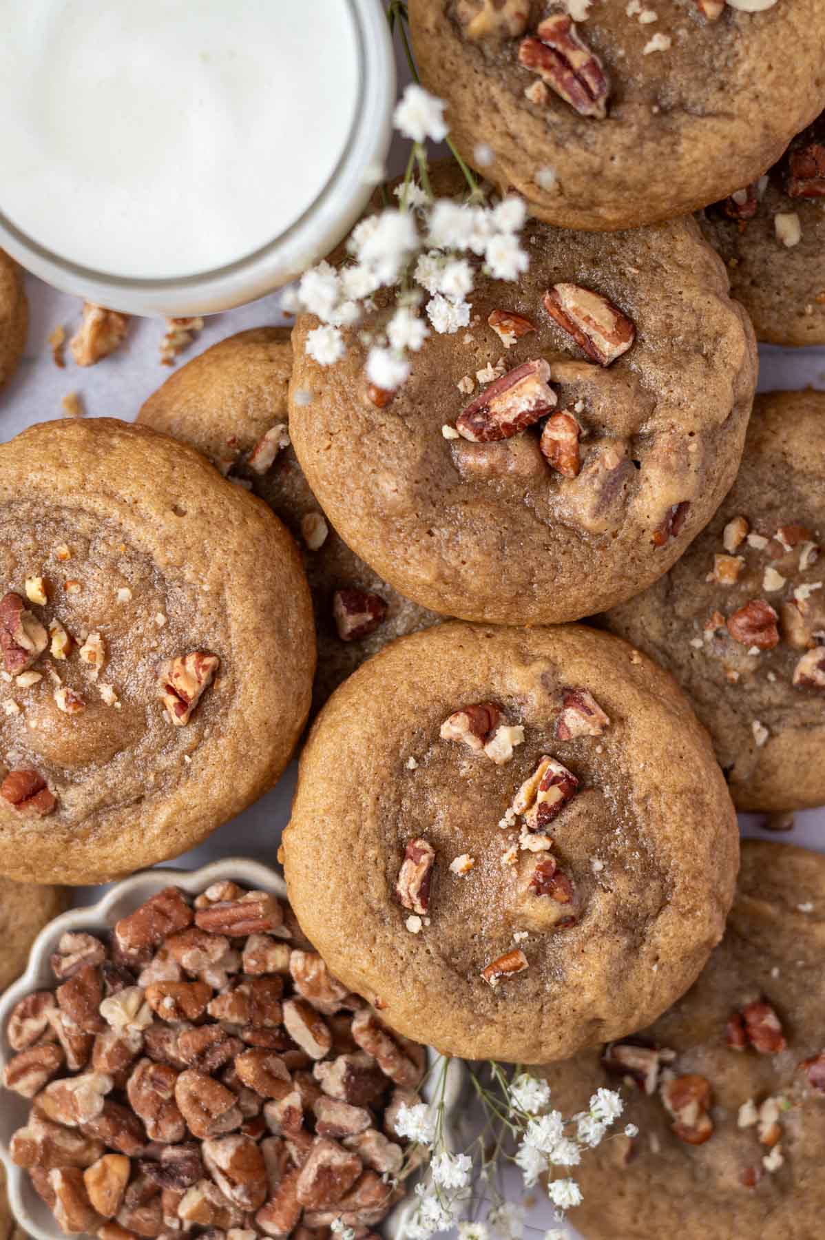 overhead look at maple pecan cookies with a glass of milk and bowl of pecans