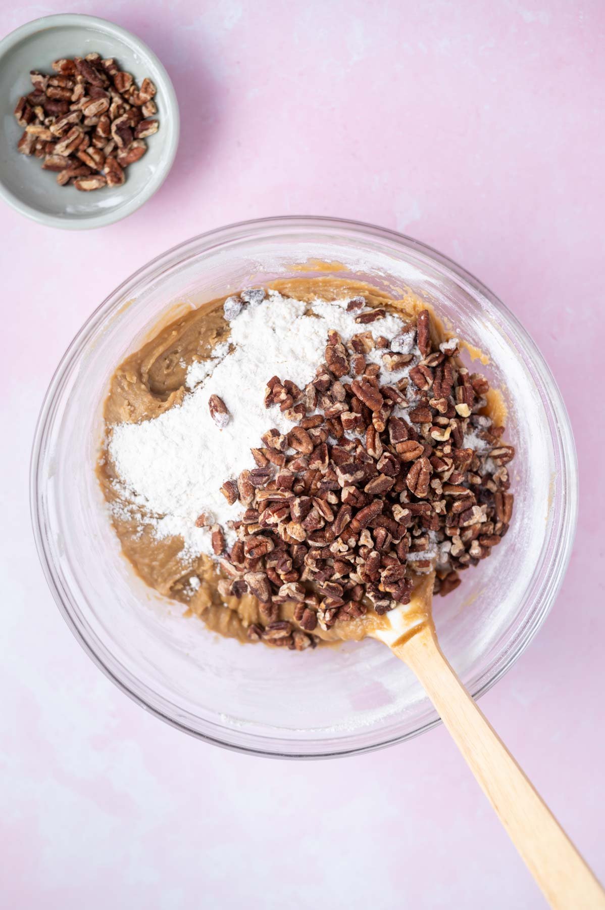 glass bowl with cookie dough with flour and pecans on top