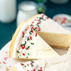 slices of sugar cookie cheesecake on a cake stand
