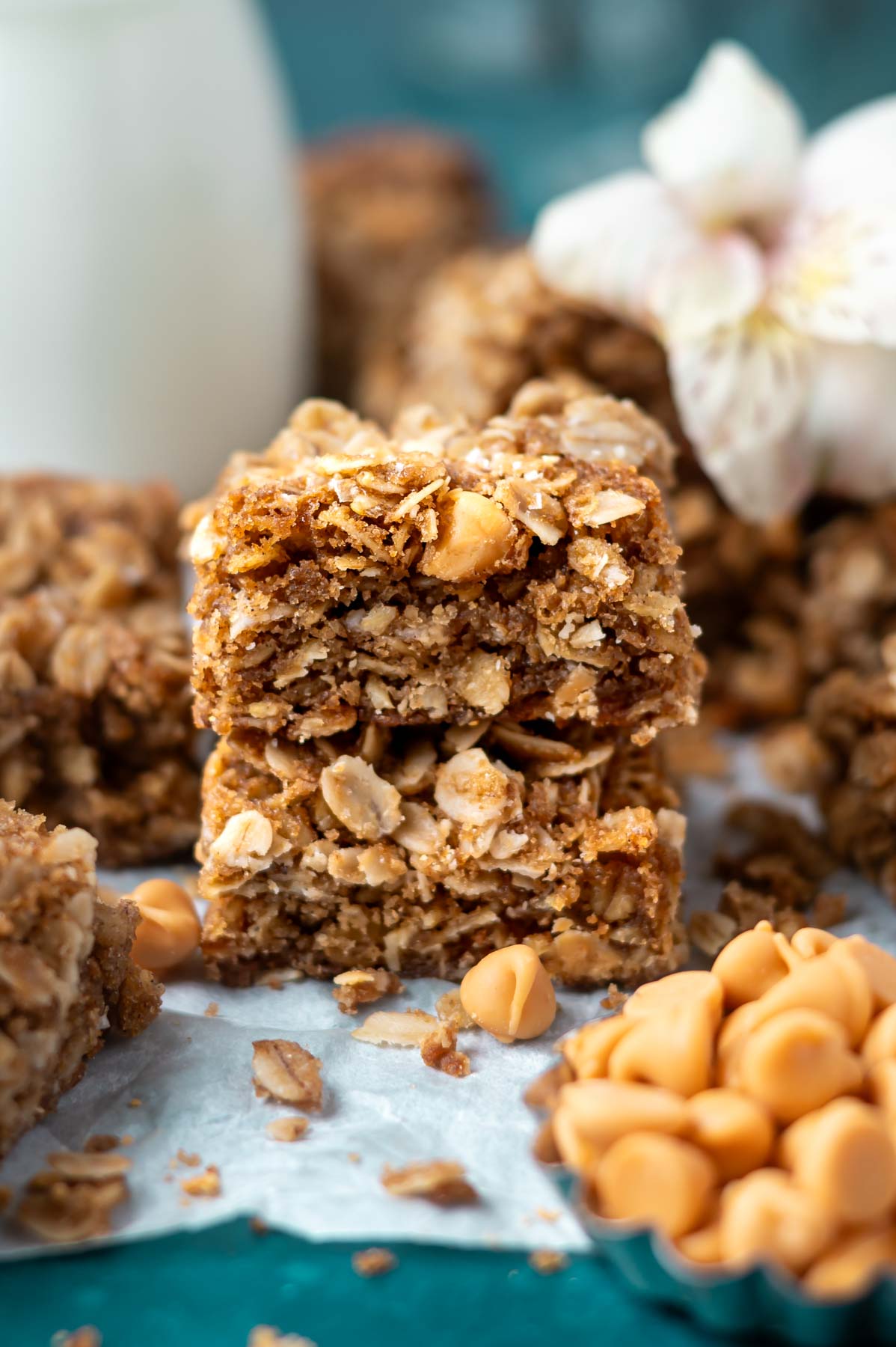 stack of butterscotch oatmeal bars with a bowl of butterscotch chips and milk in the background