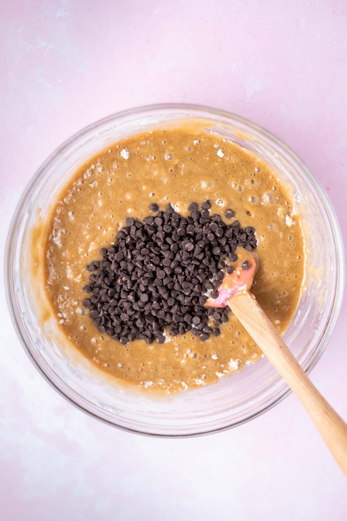 mini chocolate chips atop cake batter in a bowl with a spatula