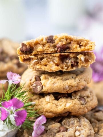 stack of coconut chocolate chip cookies with the top one broken to show soft texture
