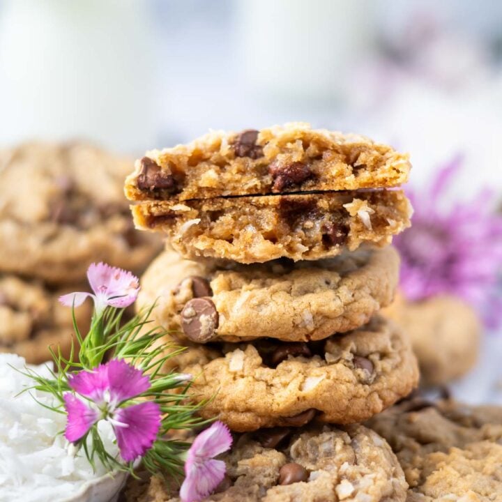 stack of coconut chocolate chip cookies with the top one broken to show soft texture