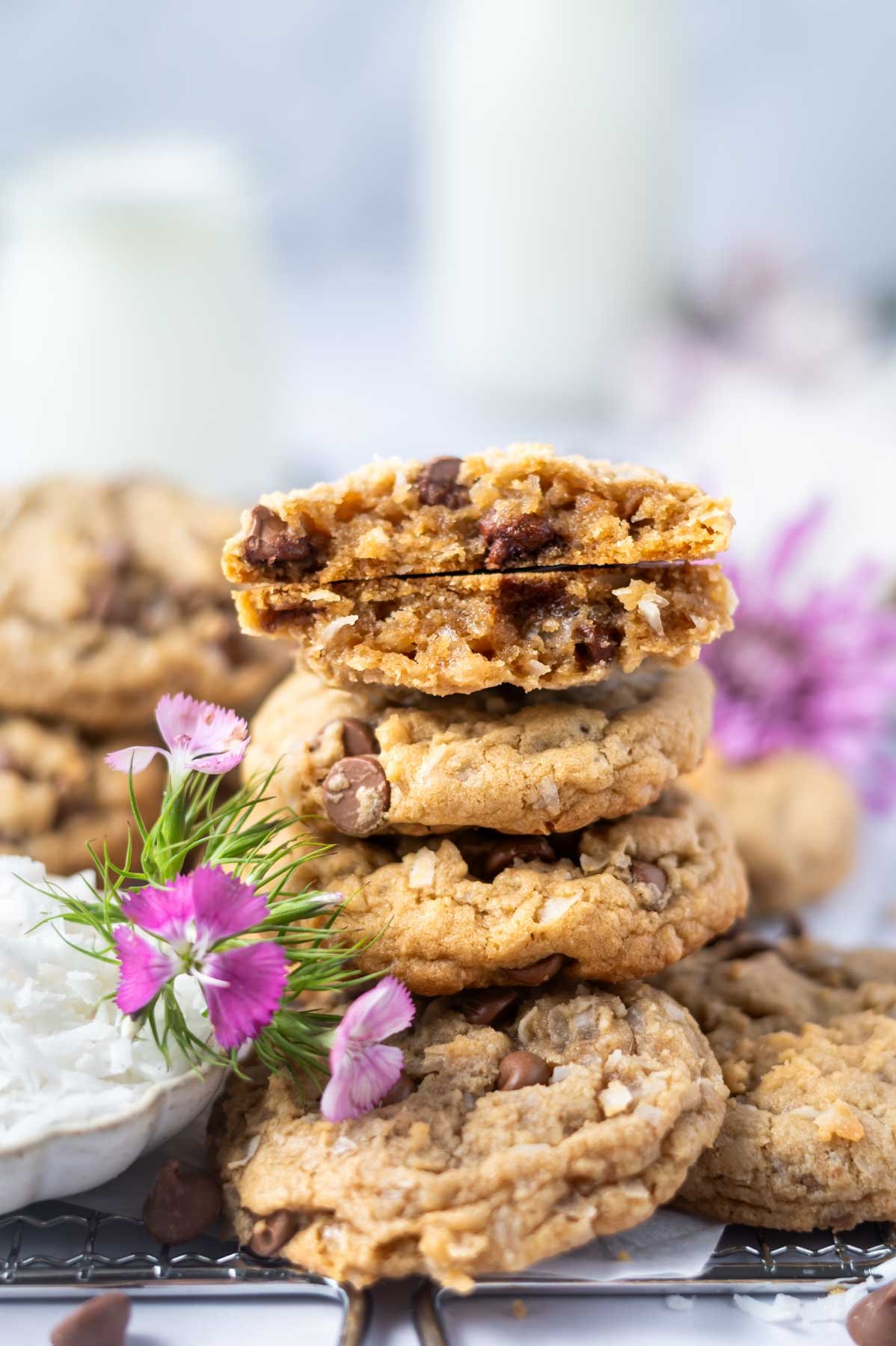 stack of coconut chocolate chip cookies with the top one broken to show soft texture