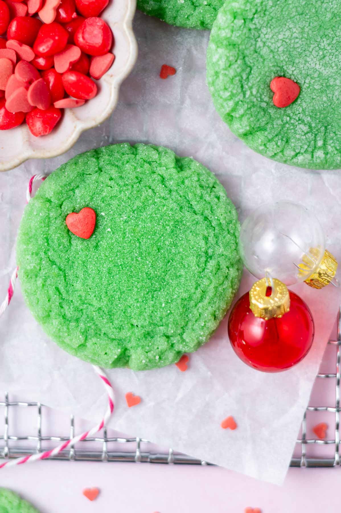 round green grinch cookie with a red heart sprinkle