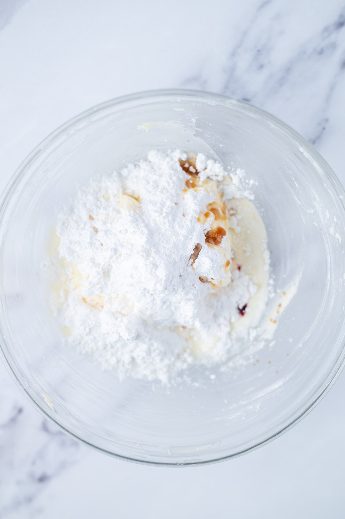 confectioners sugar, vanilla, almond, pink coloring and cream added to creamed butter in a mixing bowl