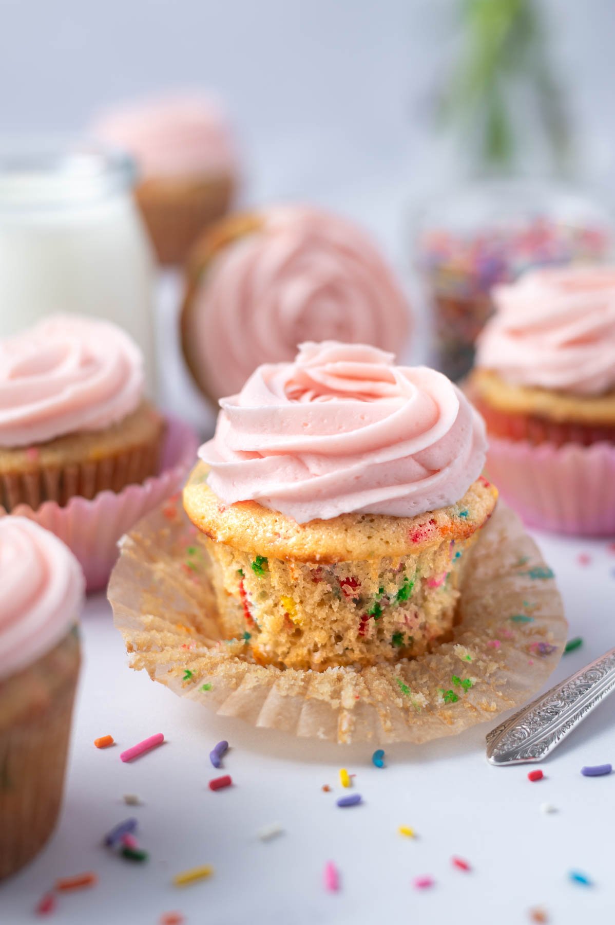 cupcake with the wrapper pulled off and a tall pink buttercream swirl