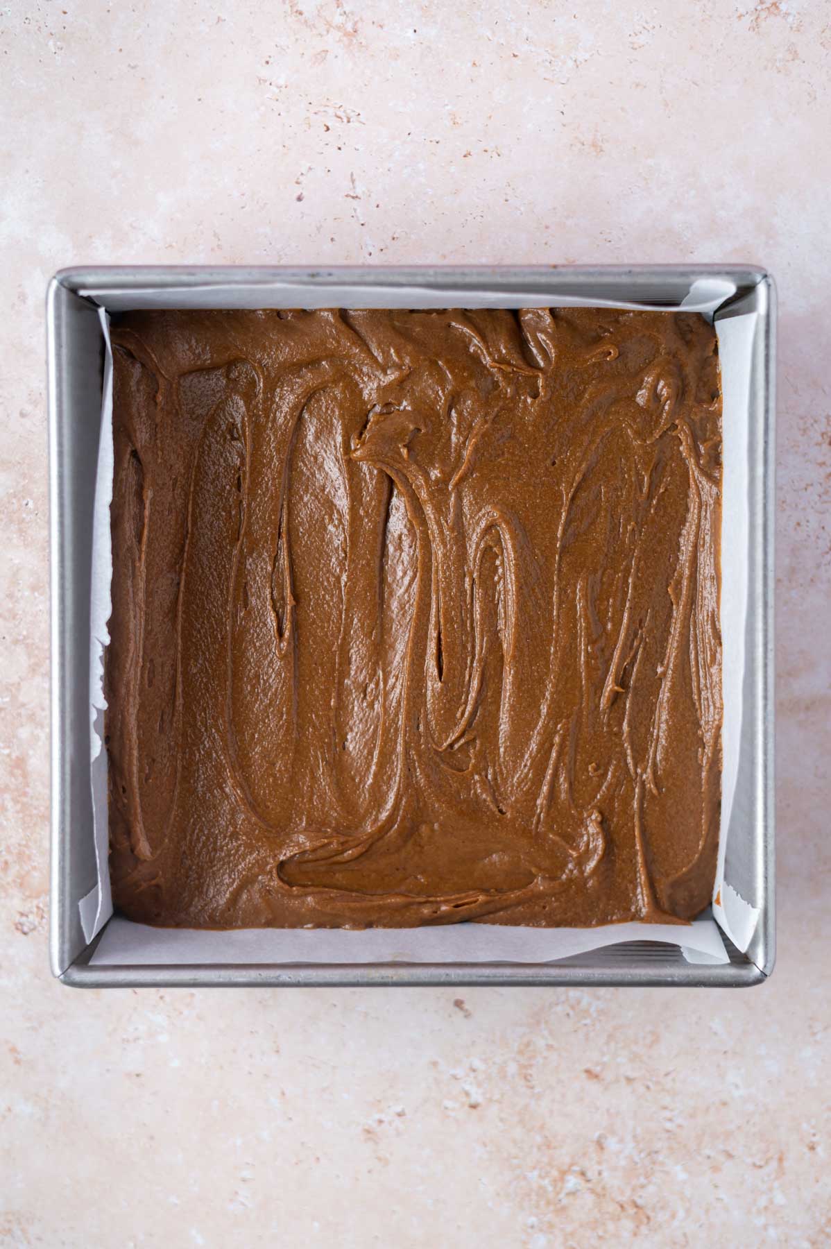 gingerbread blondie batter in a parchment lined baking pan