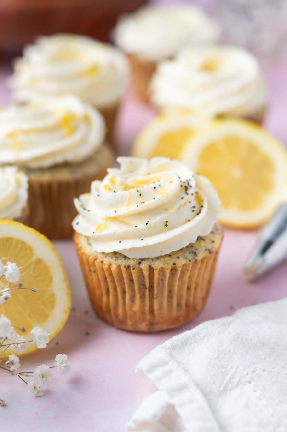lemon poppy seed cupcakes with frosting and lemon slices
