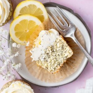 half lemon poppy seed cupcake on a plate with a fork and lemon slices