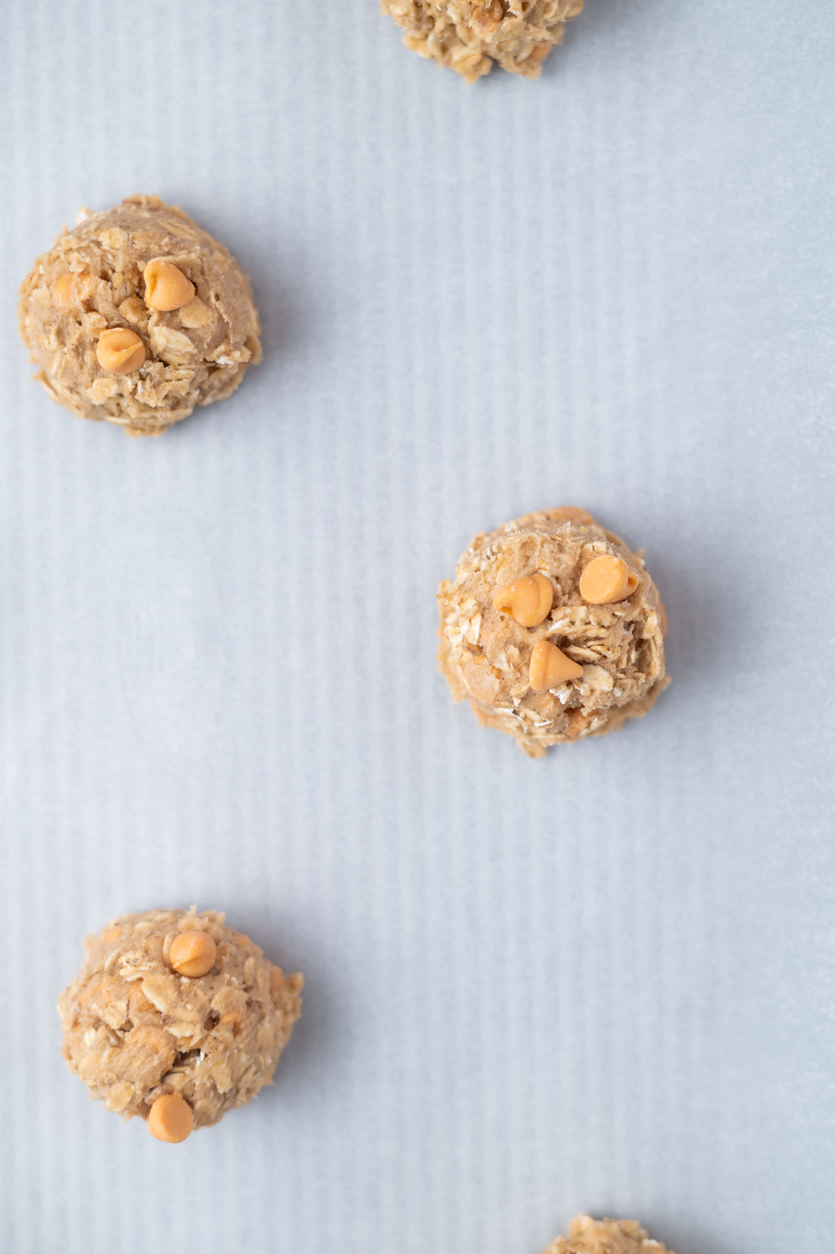 cookie dough balls on a parchment lined baking sheet pan