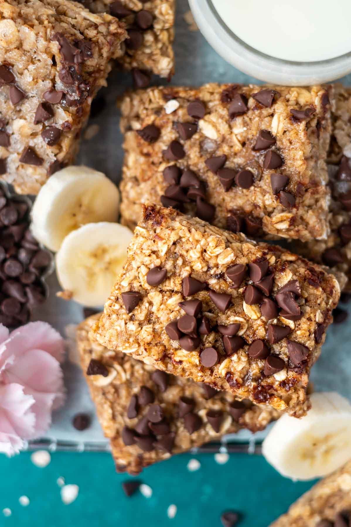overhead look at breakfast bars with chocolate chips and banana slices and a glass of milk
