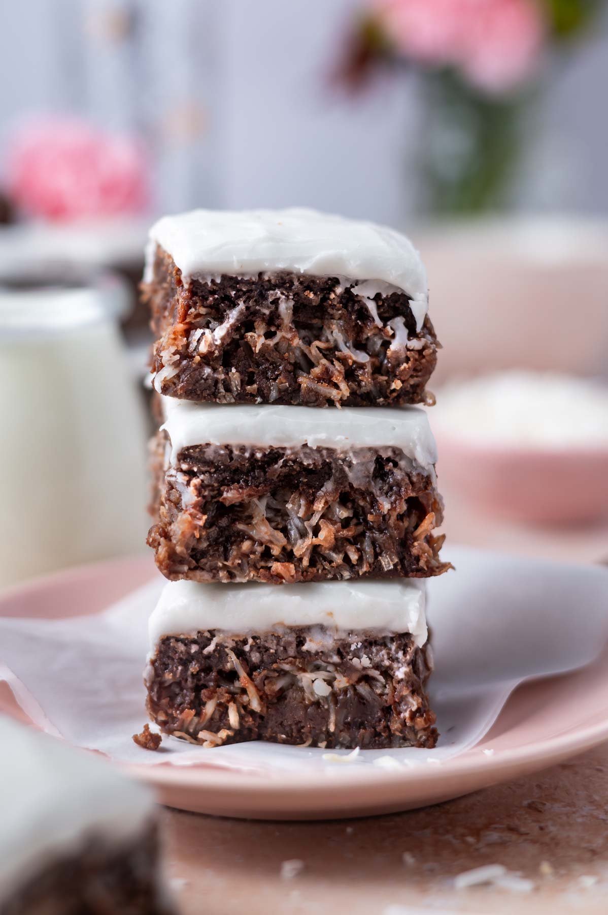 stack of three coconut glazed coconut brownies on a pink plate
