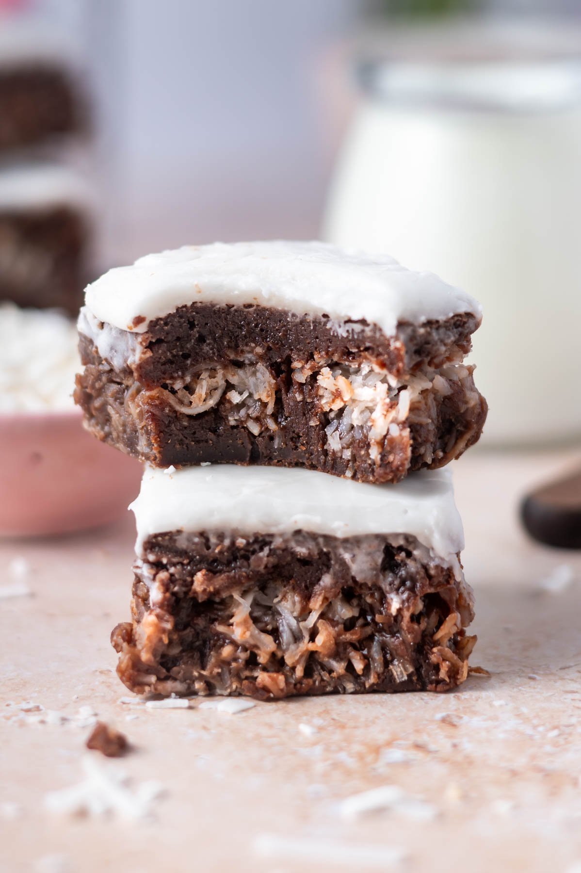 stack of brownies with coconut stuffed middle and milk in the background