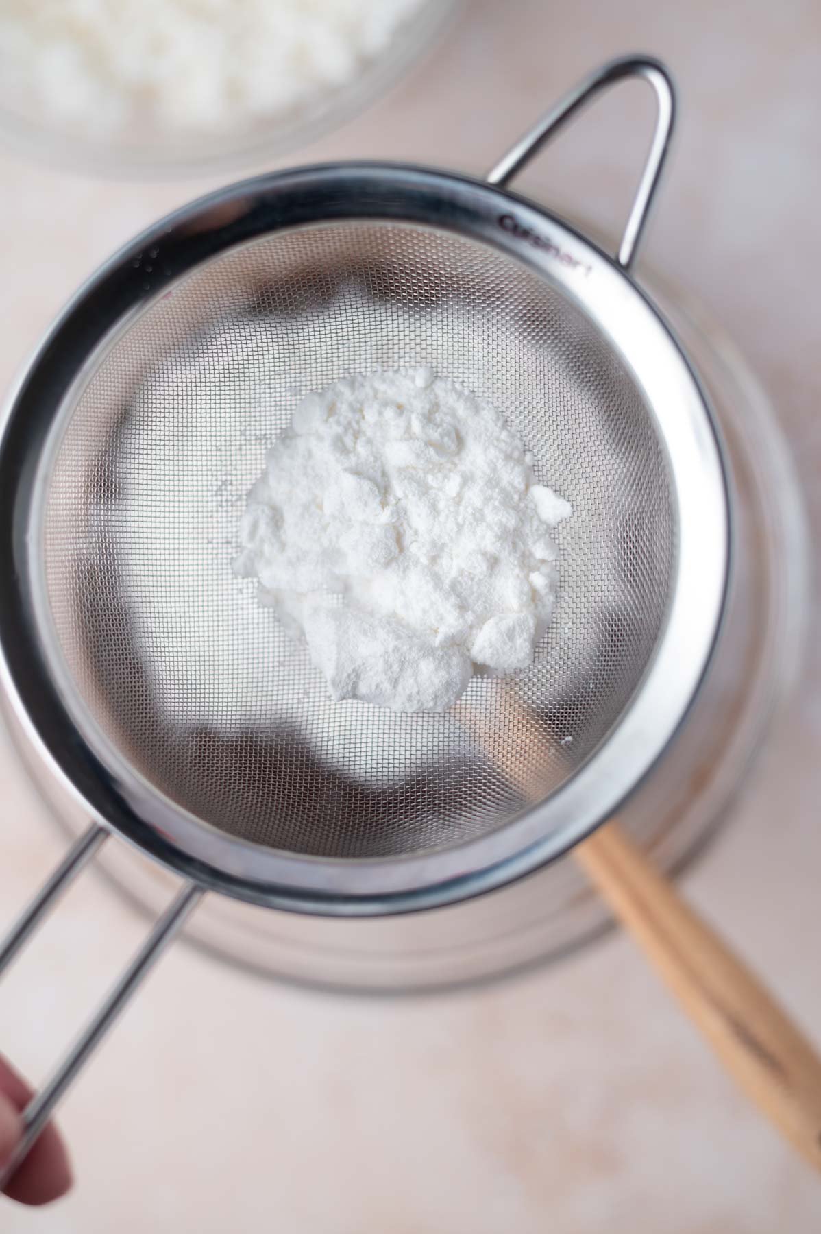 sifter over mixing bowl filled with coconut milk powder