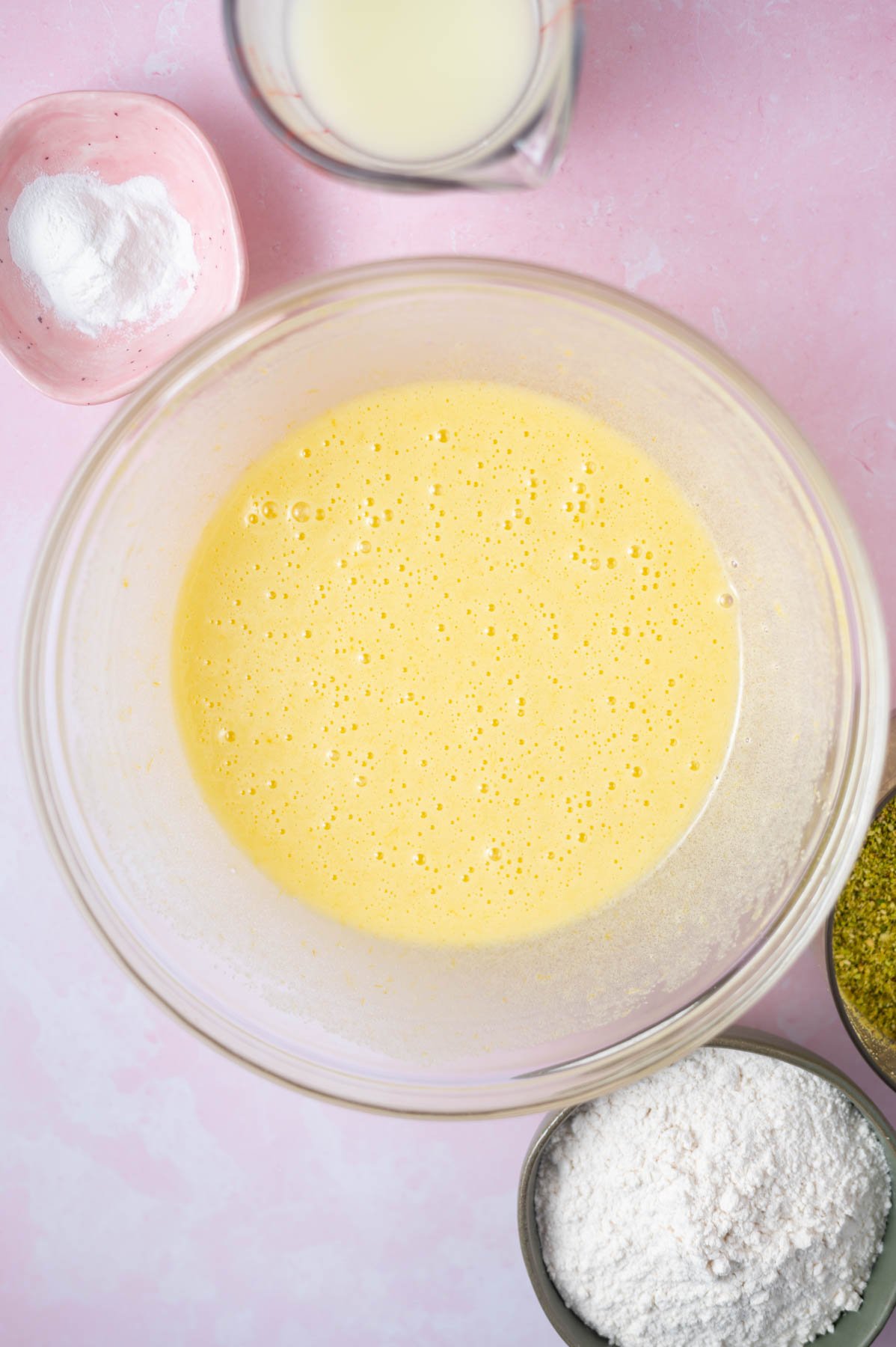 olive oil, sugar, lemon zest and eggs mixed together in a glass bowl