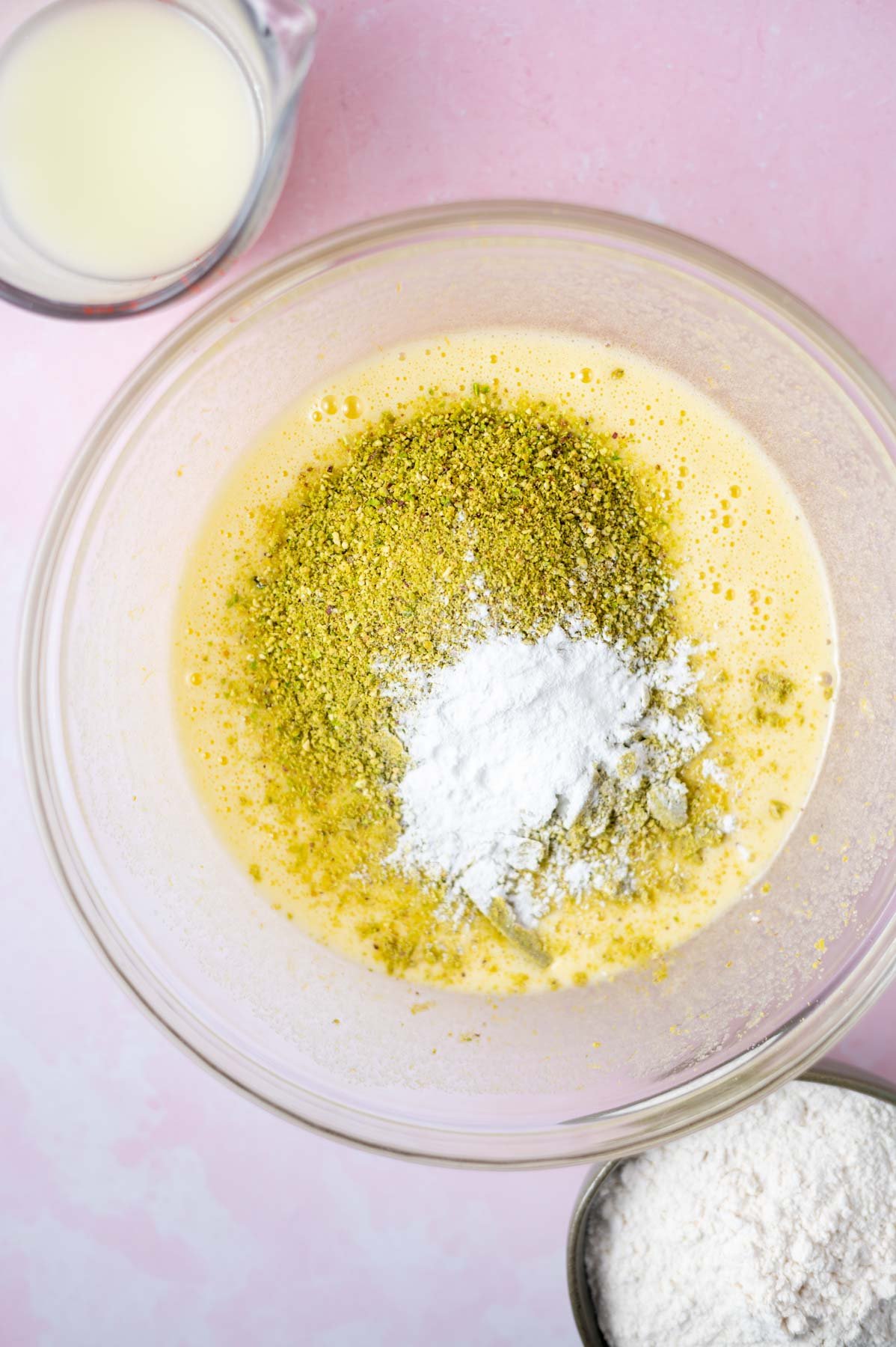ground pistachios and baking powder on top of wet ingredients in a glass bowl
