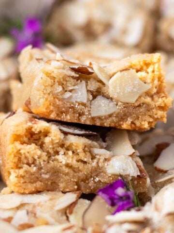 stack of two almond blondies sitting atop more blondies showing soft inside texture