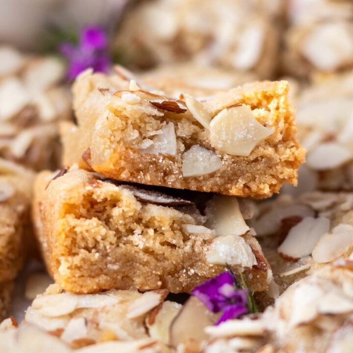 stack of two almond blondies sitting atop more blondies showing soft inside texture