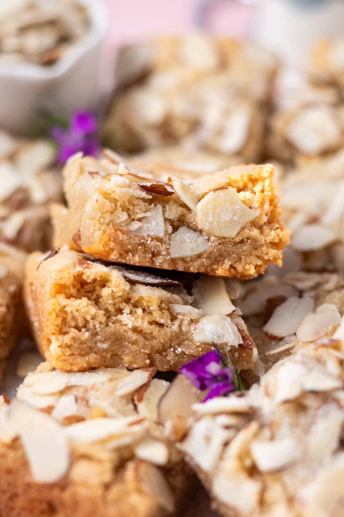 stack of two almond blondies sitting atop more blondies showing soft inside texture