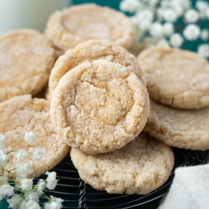 vanilla bean sugar cookies on a cooling rack with fresh flowers in the background