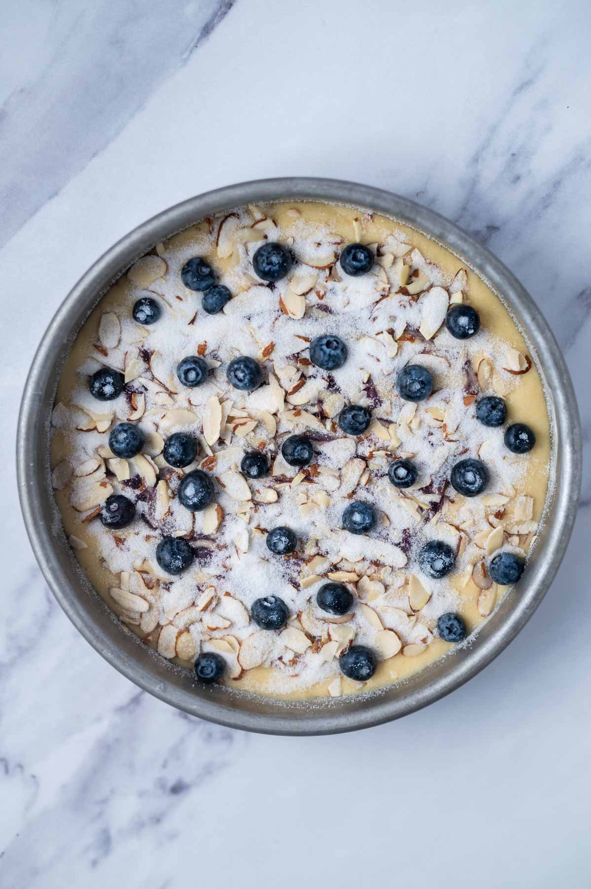 sliced almonds, fresh blueberries and granulated sugar topping over cake batter in a baking pan