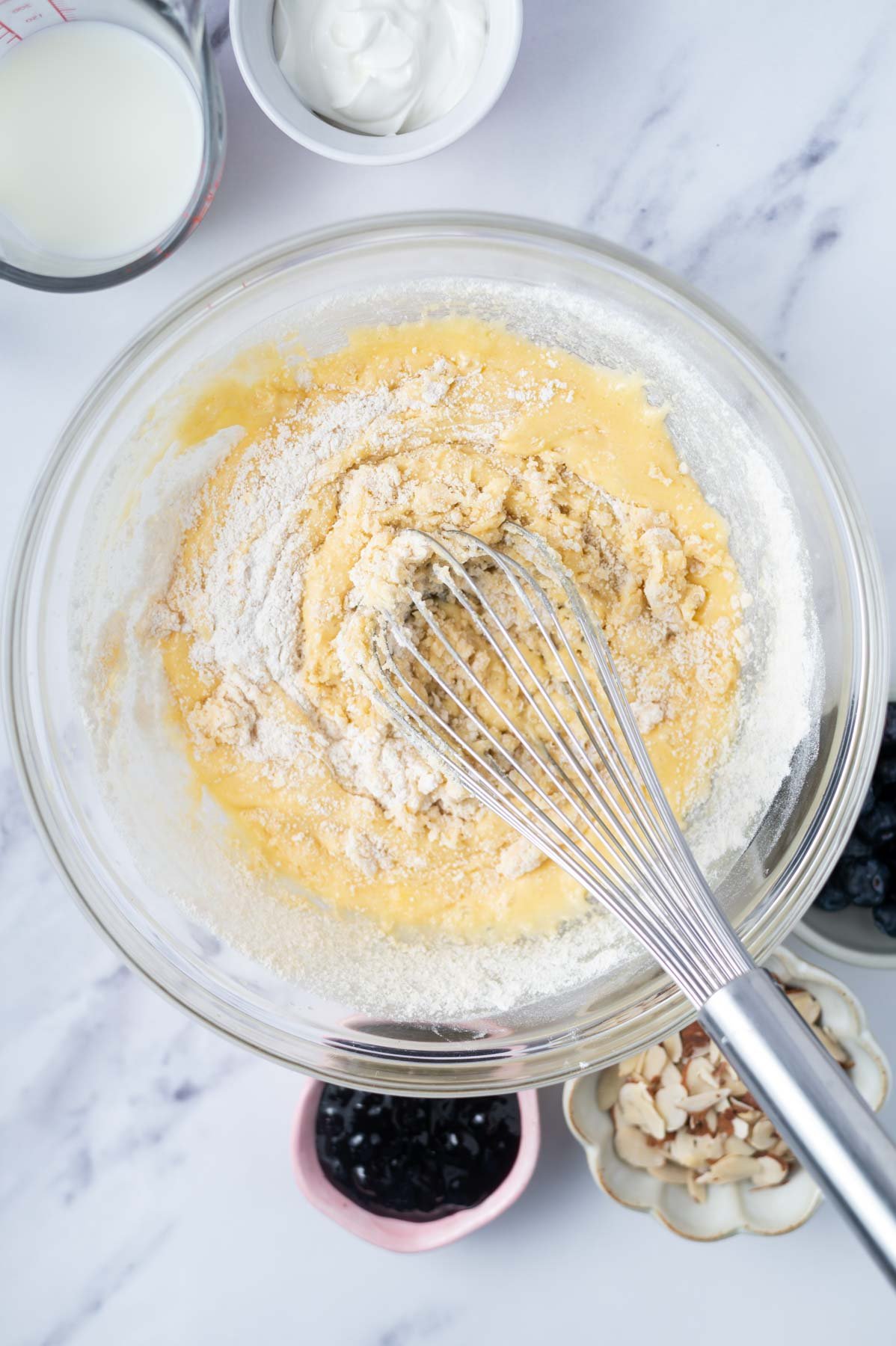 flour and almond flour still showing in cake batter in a bowl with a whisk