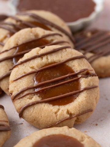 cookies leaning up against one another with a bowl of caramel in the background