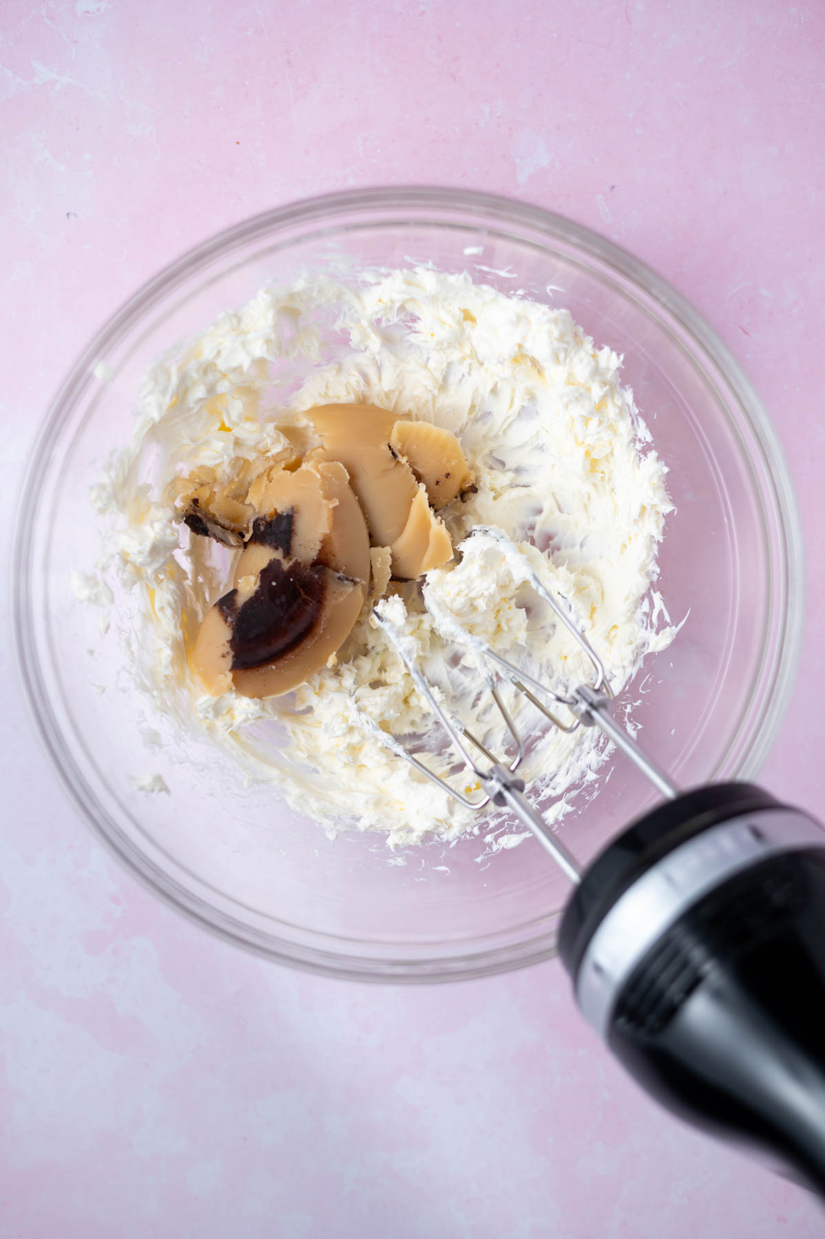 cream cheese creamed in a bowl with a hand mixer with browned butter on top