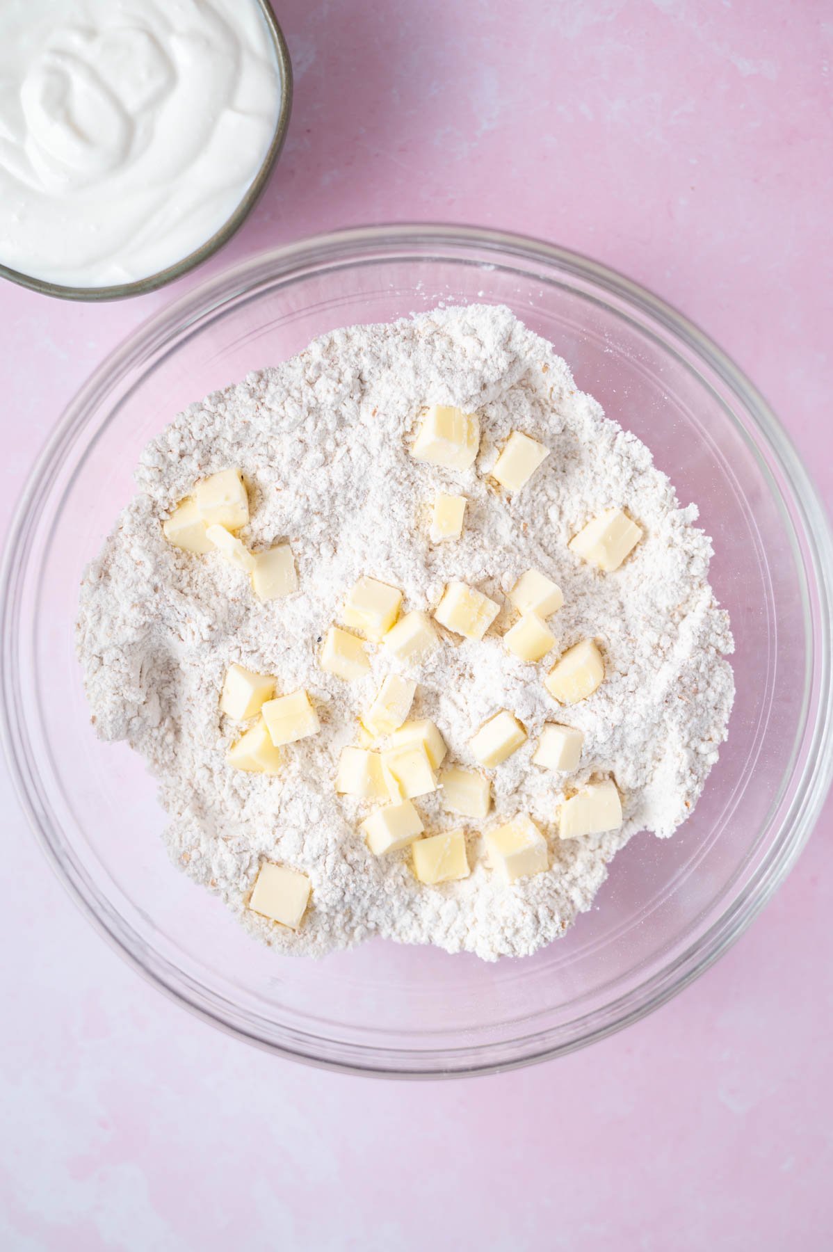 cubes of butter on top of dry ingredients in a glass bowl