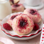 donuts with jam filled middles on a plate with a glass of milk and coffee in the background