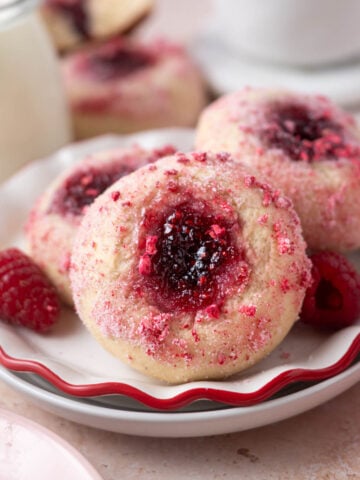 donuts with jam filled middles on a plate with a glass of milk and coffee in the background