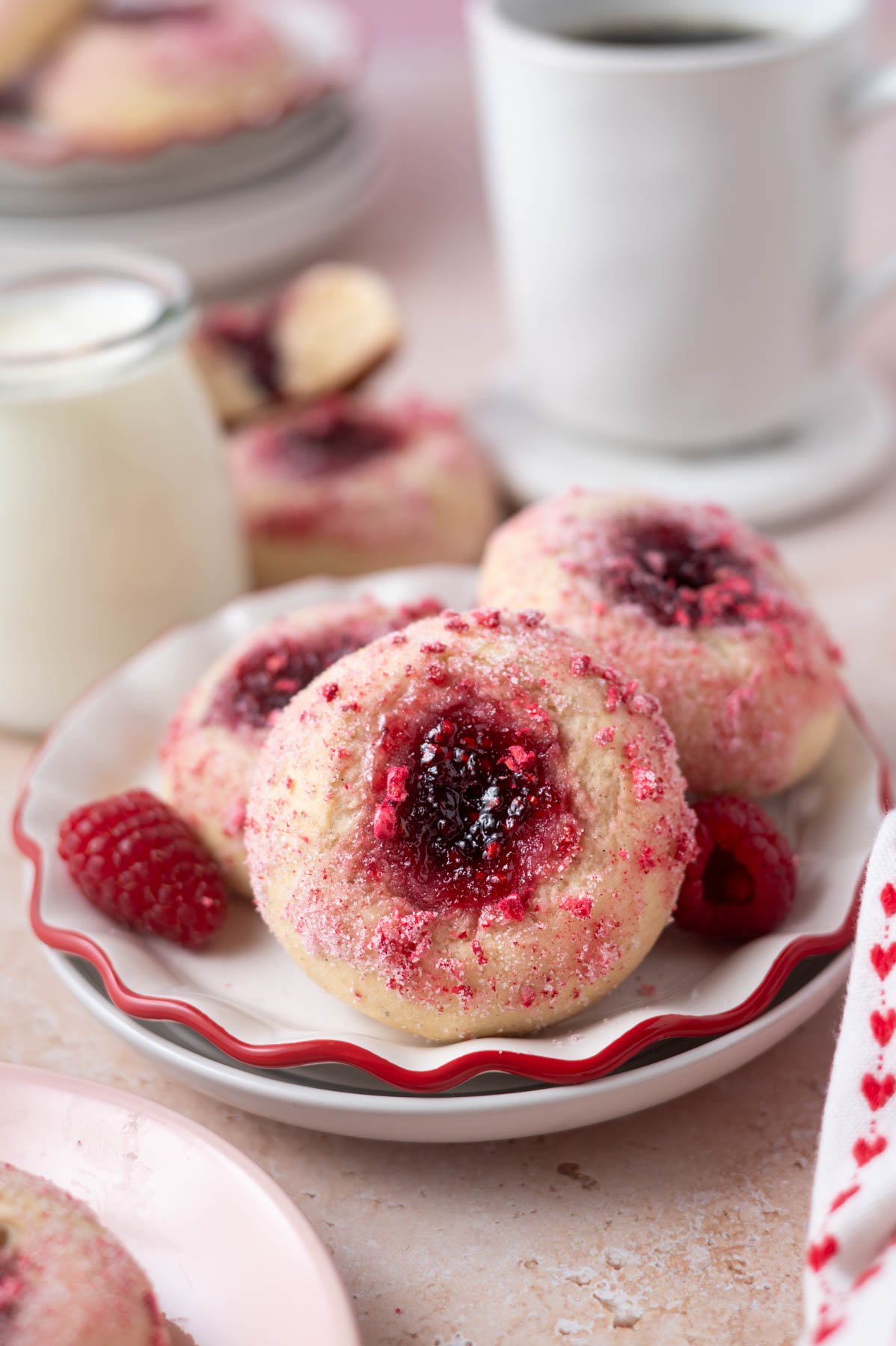 donuts with jam filled middles on a plate with a glass of milk and coffee in the background