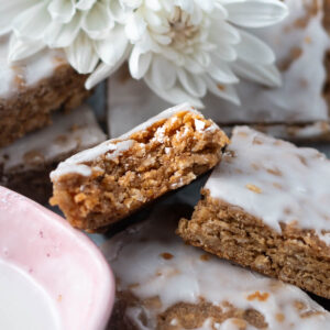 iced oatmeal cookie bar with a bite missing in a pile of cookie bars