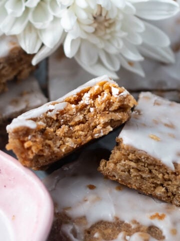 iced oatmeal cookie bar with a bite missing in a pile of cookie bars