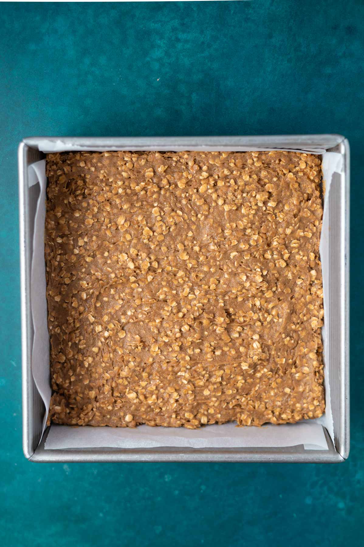 cookie bar dough smoothed into an 8x8 pan