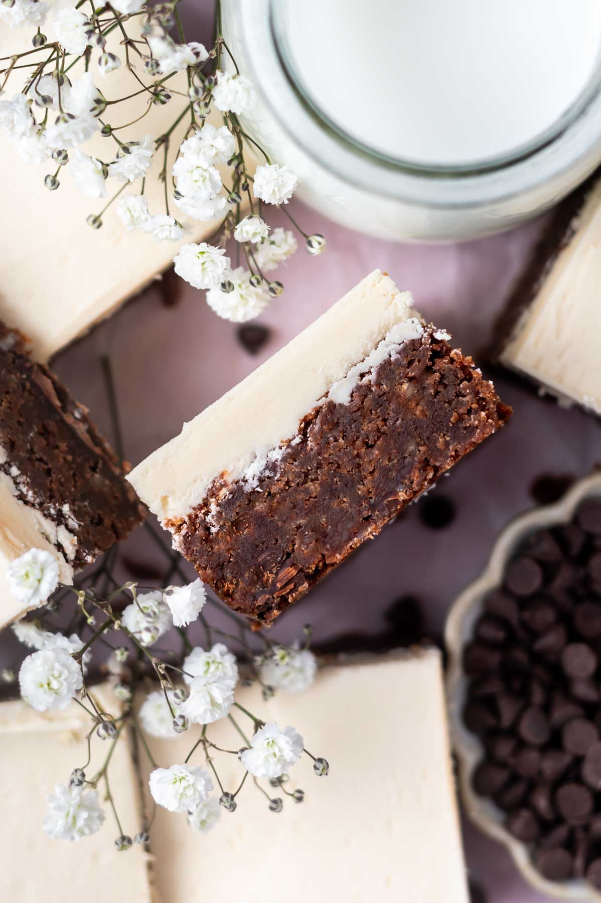overhead look at the inside of an Irish cream brownie with frosting with fresh white flowers and a glass of milk nearby