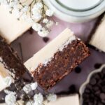 overhead look at the inside of an Irish cream brownie with frosting with fresh white flowers and a glass of milk nearby