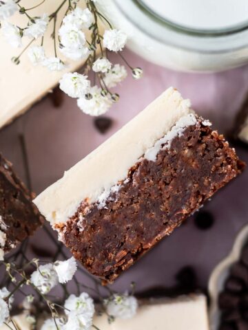 overhead look at the inside of an Irish cream brownie with frosting with fresh white flowers and a glass of milk nearby