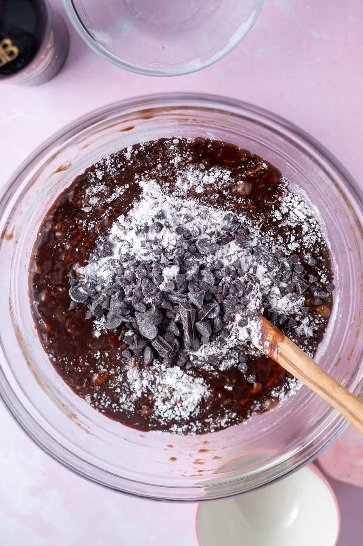 flour and chocolate chips being mixed into batter with a spatula