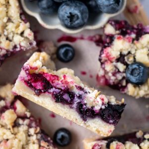 blueberry crumble bar on its side showing jammy blueberry filling, shortbread bottom and oat crumble topping