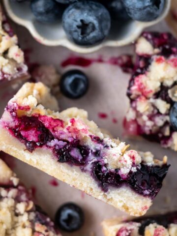 blueberry crumble bar on its side showing jammy blueberry filling, shortbread bottom and oat crumble topping