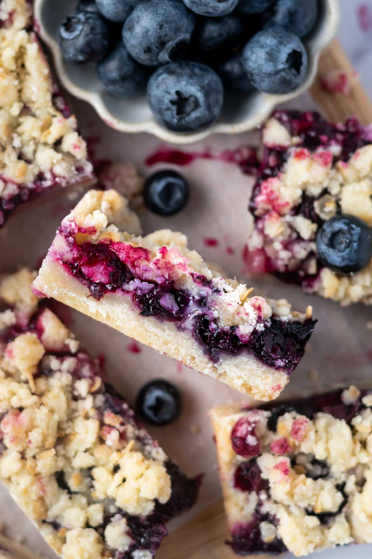 blueberry crumble bar on its side showing jammy blueberry filling, shortbread bottom and oat crumble topping