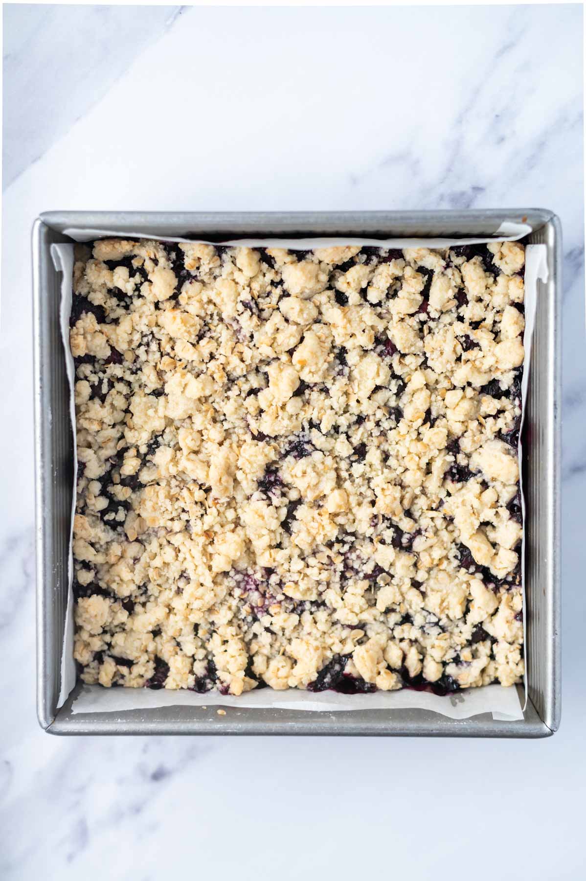 baked blueberry crumble bars in a parchment lined baking pan