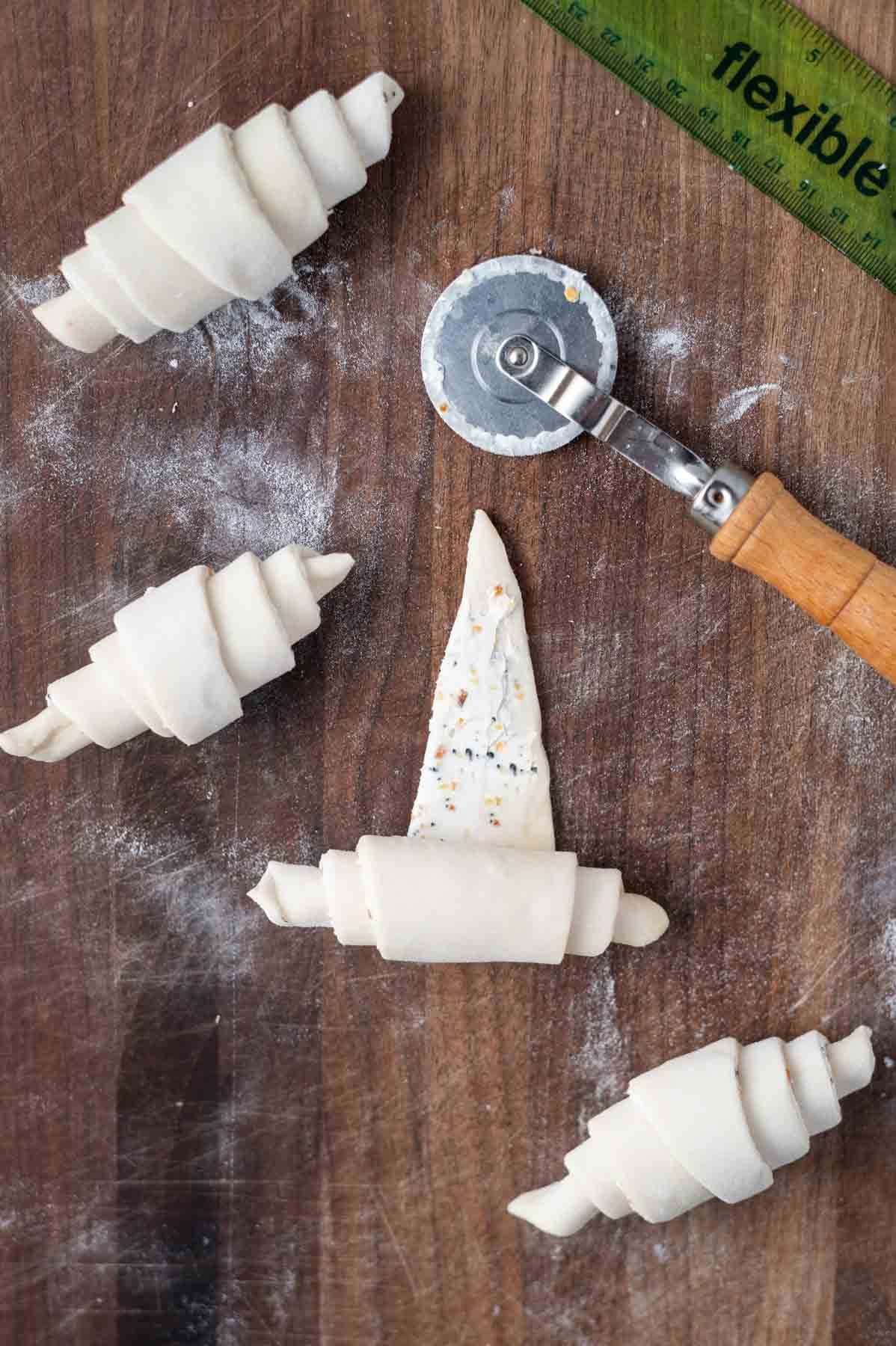 mini croissants rolled on a cutting board with a pastry cutting wheel and a ruler