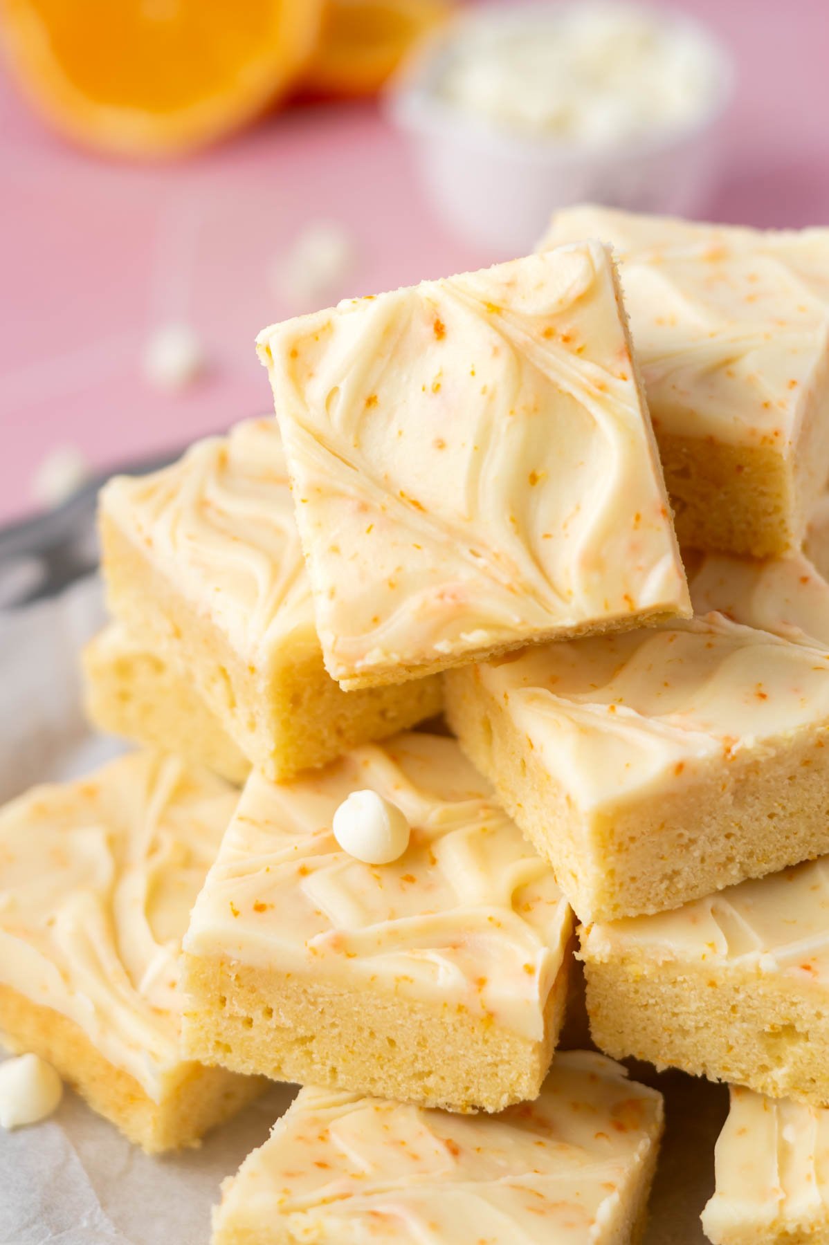 pile of orange creamsicle bars on a plate with orange slices and white chocolate chips