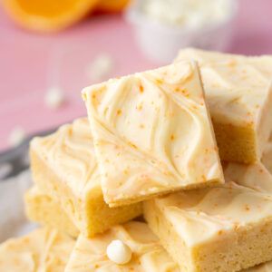 pile of orange creamsicle bars on a plate with orange slices and white chocolate chips