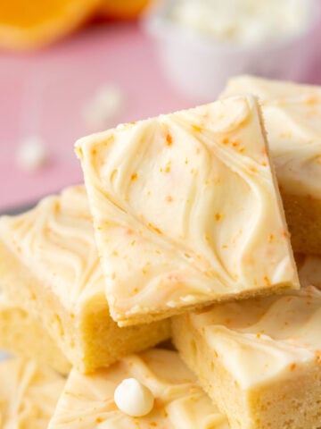 pile of orange creamsicle bars on a plate with orange slices and white chocolate chips