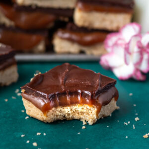 caramel slice bar with a bite missing on a green counter