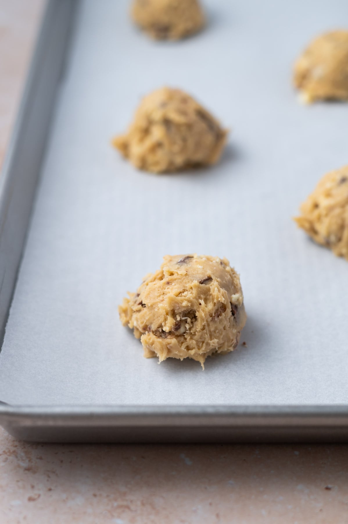 cookie dough balls on a parchment lined baking pan
